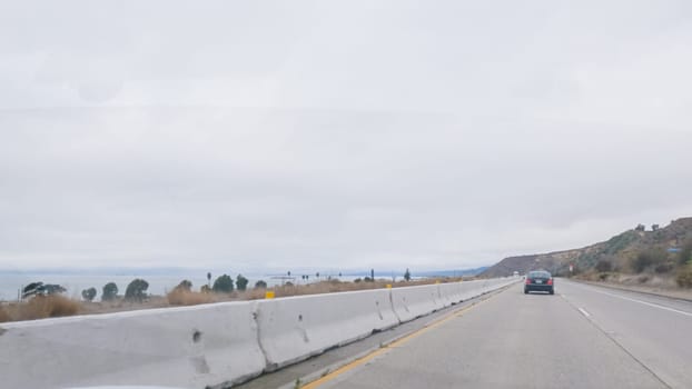 Los Angeles, California, USA-December 4, 2022-POV-Driving along Highway 101 near Rincon Beach, California, amidst a gloomy, cloudy winter day.