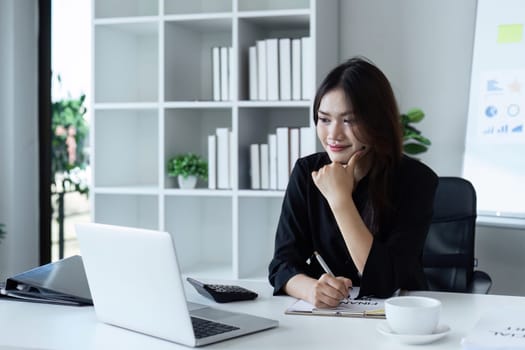 Businesswoman working on laptop with using a calculator to calculate the numbers reading finance accounting concept.