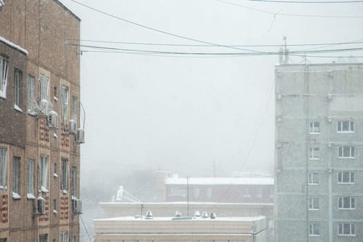 Tall apartment buildings covered with snow in a residential area of the city during a blizzard in the middle of winter