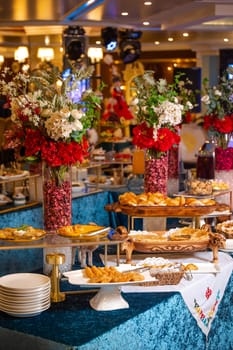 A beautifully decorated table is laden with a variety of delicious pastries, bread, and floral centerpieces.