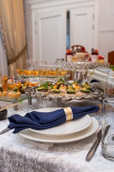 A beautifully set table with a blue napkin, silverware, and a glass of water. The table is decorated with flowers and candles.