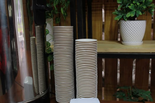 Photo disposable paper cups for coffee. The interior of the coffee shop. Disposable tableware. Ecology.