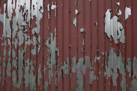 Photo the peeling paint of a painted brown corrugated board fence. Painting.