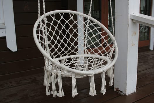 Photo a white hanging knitted armchair on the porch of the house. Outdoor recreation. Macrame.