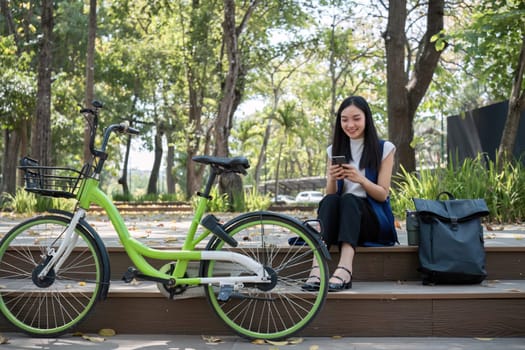 Asian business woman sitting and working in a nature park Travel by bicycle to save the environment.