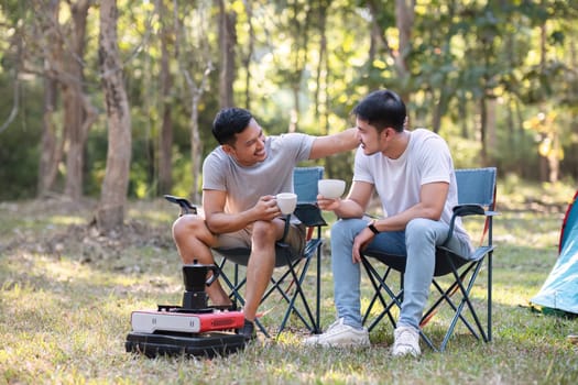 Asian LGBTQ couple drinking coffee in a romantic camping tent. LGBTQ couple drinking coffee in a camping tent, enjoying nature, forest, camping atmosphere, LGBTQ, gay, gay men..