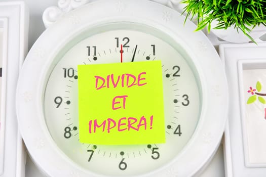Latin quote Divide et impera meaning Divide and conquer. the best method of governing such a state is to incite and use hostility between its parts. Text written on the yellow sticker on the watch