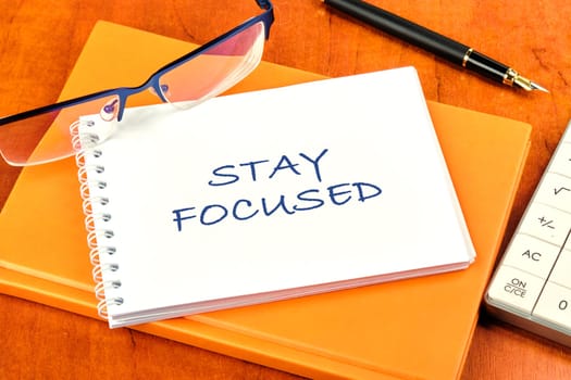 Motivation concept. STAY FOCUSED written on a clean white notebook