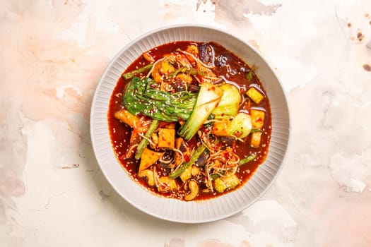 Red curry with veggies, tofu on a white background. Made with coconut milk, red curry paste, garnished with sesame seeds.