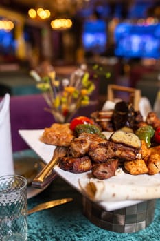 assorted different kebabs on a white plate in a restaurant.