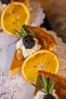 A decadent display of four slices of creamy cheesecake adorned with vibrant orange slices and juicy blackberries on a dainty white doily.