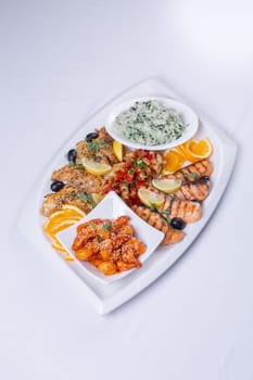 seafood mixture. Delicious grilled fish, shrimp in sauce and salmon on the table top vie.