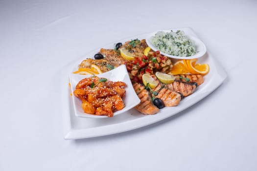 seafood mixture on a white grill. Delicious grilled fish, shrimp in sauce and salmon on the table.