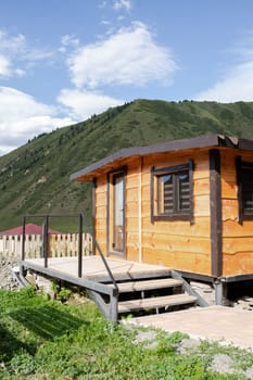 Wooden sauna in summer at the house with a mountain landscape in the background.