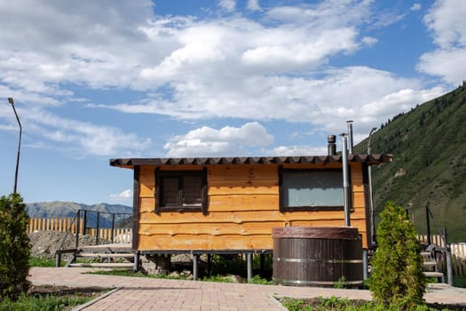 Wooden sauna in summer at the house with a mountain landscape in the background.