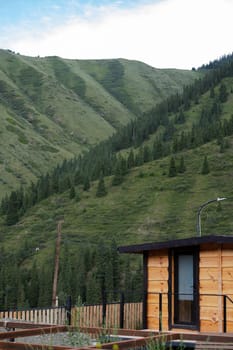 Wooden sauna in summer at the house with a mountain landscape in the background.