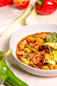 Red curry with veggies, tofu on a white background. Made with coconut milk, red curry paste, garnished with sesame seeds.