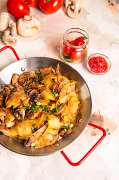 Sliced potatoes, fresh mushrooms, and diced onions sizzling in a frying pan on a clean white background, ready to be cooked.