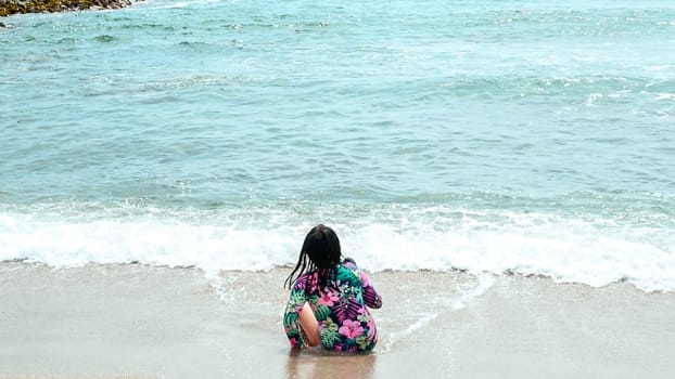 Happy girl sitting on the water's edge in the beautiful beach of San Bartolo south of Lima - Peru. Summer Vacation