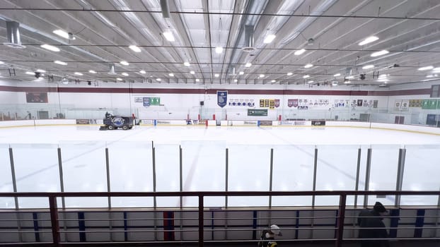 Denver, Colorado, USA-February 17, 2024-ice resurfacer moves across the surface of an empty hockey rink, surrounded by banners and seating, preparing the ice for athletes and skaters.