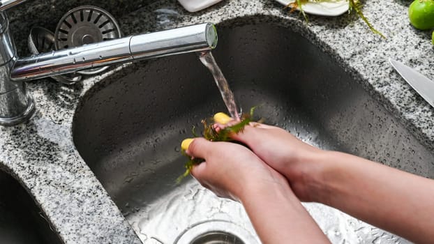 Young hands wash supplies for the preparation of ceviche in the kitchen sink. Raw healthy food