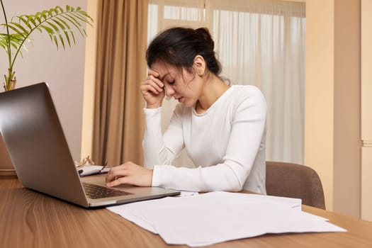 Stressed tired woman working at laptop at home