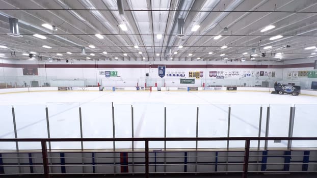 Denver, Colorado, USA-February 17, 2024-ice resurfacer moves across the surface of an empty hockey rink, surrounded by banners and seating, preparing the ice for athletes and skaters.