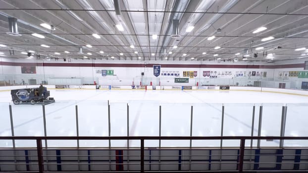 Denver, Colorado, USA-February 17, 2024-ice resurfacer moves across the surface of an empty hockey rink, surrounded by banners and seating, preparing the ice for athletes and skaters.