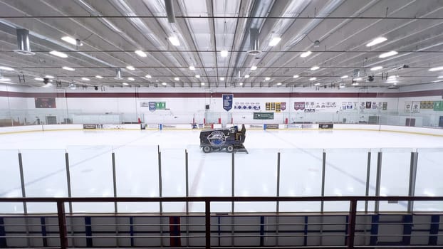 Denver, Colorado, USA-February 17, 2024-ice resurfacer moves across the surface of an empty hockey rink, surrounded by banners and seating, preparing the ice for athletes and skaters.