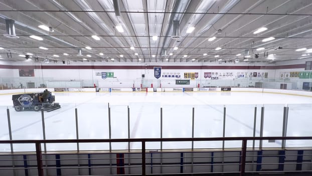 Denver, Colorado, USA-February 17, 2024-ice resurfacer moves across the surface of an empty hockey rink, surrounded by banners and seating, preparing the ice for athletes and skaters.