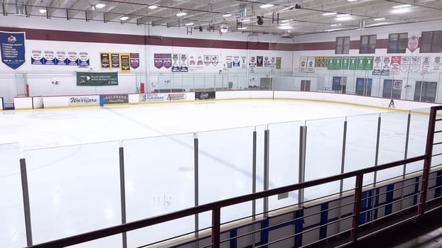 Denver, Colorado, USA-February 17, 2024-ice resurfacer moves across the surface of an empty hockey rink, surrounded by banners and seating, preparing the ice for athletes and skaters.