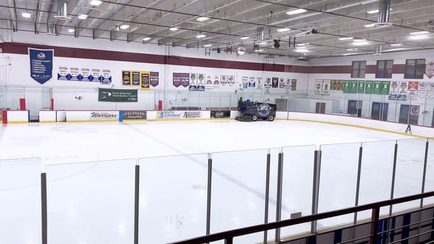 Denver, Colorado, USA-February 17, 2024-ice resurfacer moves across the surface of an empty hockey rink, surrounded by banners and seating, preparing the ice for athletes and skaters.