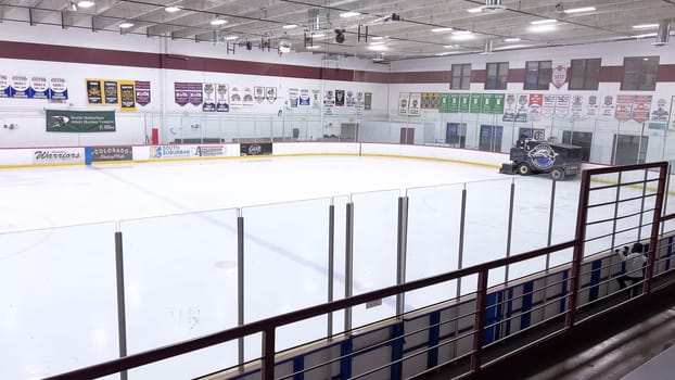 Denver, Colorado, USA-February 17, 2024-ice resurfacer moves across the surface of an empty hockey rink, surrounded by banners and seating, preparing the ice for athletes and skaters.