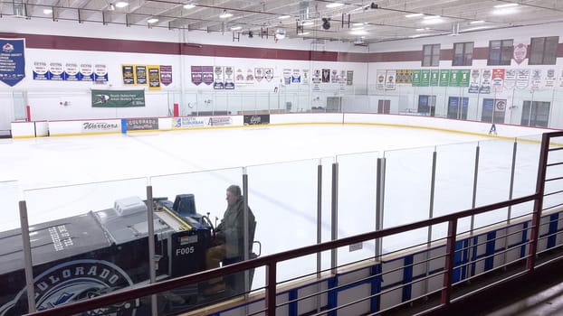 Denver, Colorado, USA-February 17, 2024-ice resurfacer moves across the surface of an empty hockey rink, surrounded by banners and seating, preparing the ice for athletes and skaters.