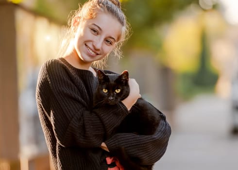 Teenage Girl Holds Black Cat In Her Hands, A Portrait With A Pet At Home