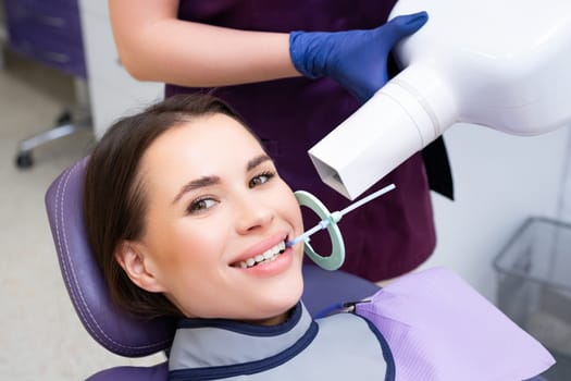 A patient smiles happily while undergoing a teeth X ray at the dental clinic