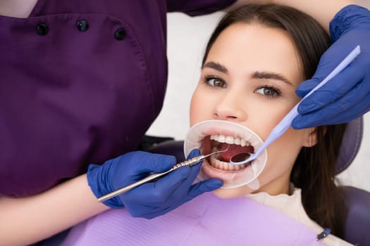 Portrait of brunette woman has checkup of teeth in denstist clinic.