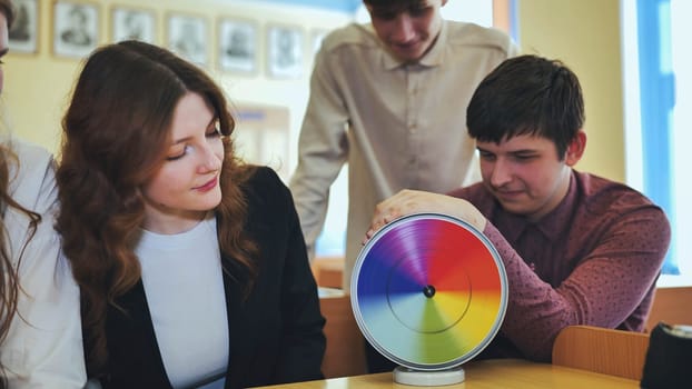 Students in physics class spin Newton's multicolored disk