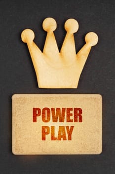 Business concept. On a black background there is a wooden crown of the leader and a sign with the inscription - Power Play