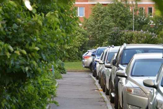 Moscow, Russia. Row of cars parked along sidewalk near house