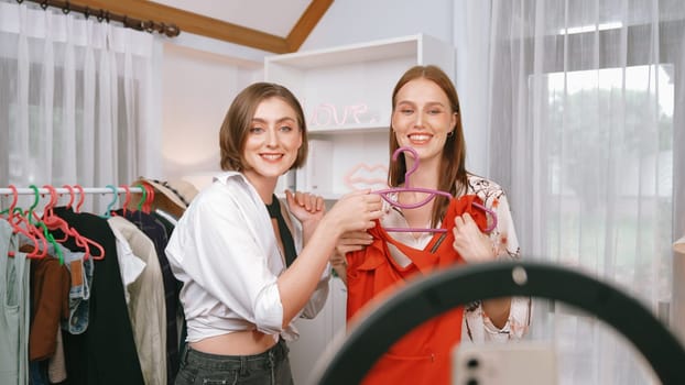 Two women influencer shoot live streaming vlog video review clothes prim social media or blog. Happy young girl with apparel studio lighting for marketing recording session broadcasting online.