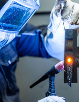 Welder worker welding pieces of metal in the industrial factory, heavy weld industry concept
