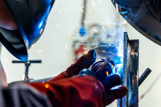 Welder worker welding pieces of metal in the industrial factory, heavy weld industry concept