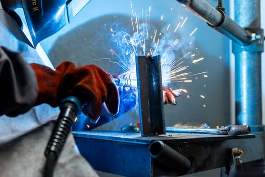 Welder worker welding pieces of metal in the industrial factory, heavy weld industry concept