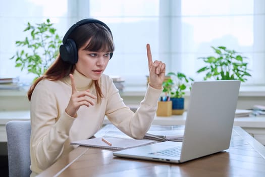 Teenage girl college student in headphones having video conference chat online meeting lesson webinar on computer laptop screen, sitting at desk at home. E-learning, education, technology, knowledge