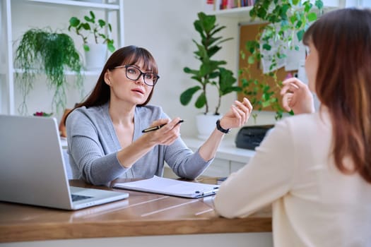 Middle-aged female psychologist, psychotherapist, counselor, social worker working with young woman patient. Psychology therapy professional help consultation treatment support mental health concept