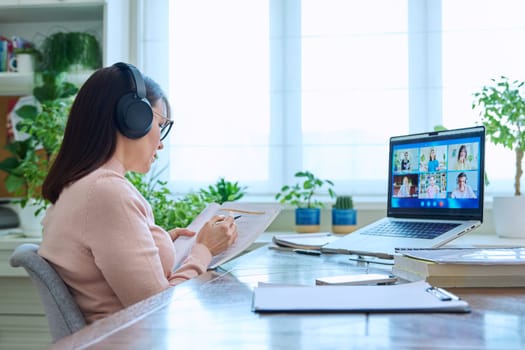 Woman teacher in headphones teaching online, high school students on laptop computer screen, video conference. Remote meeting, consultation, e lesson, training, education, technology concept