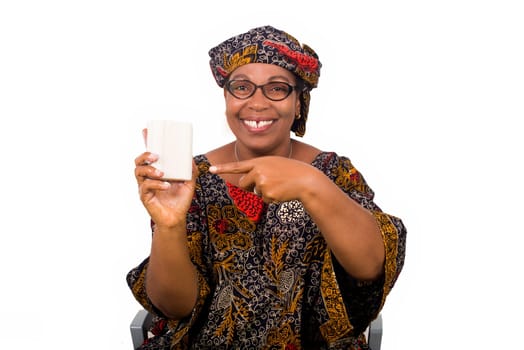Happy woman dressed in african outfit with scarf on head holds and presents white soap to camera with hand gesture isolated on white background.