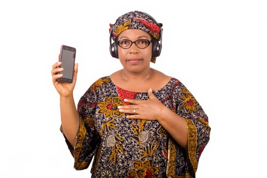 mature african woman in loincloth listening music using headphones and cellphone having hand gesture