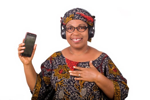 mature african woman in loincloth listening music using headphones and cellphone having hand gesture